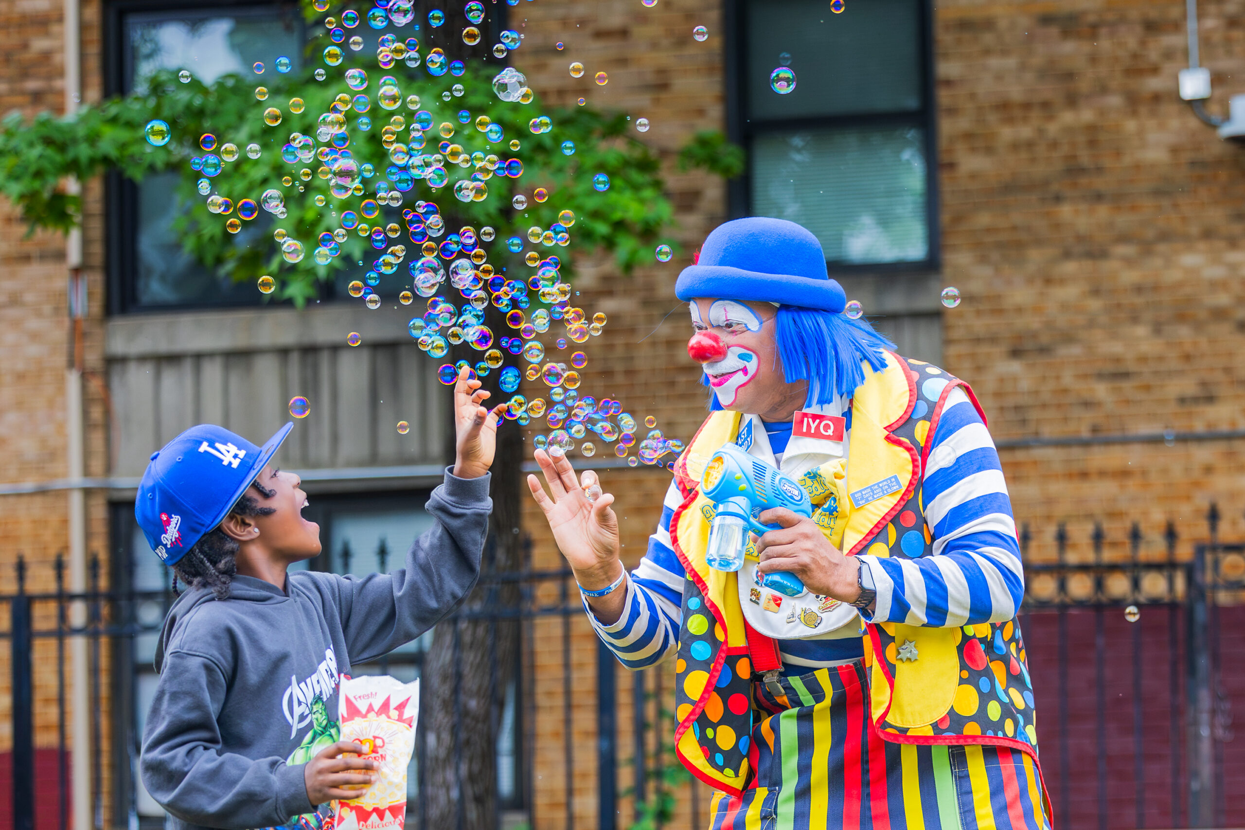 A DCHA child resident smiles as event staff blow bubbles in the air.